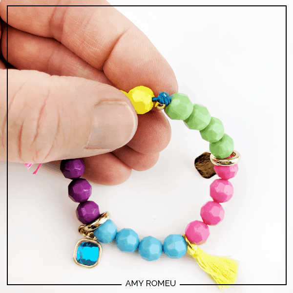 knotted cord while making a stretchy stack bracelet with beads, charms and tassels