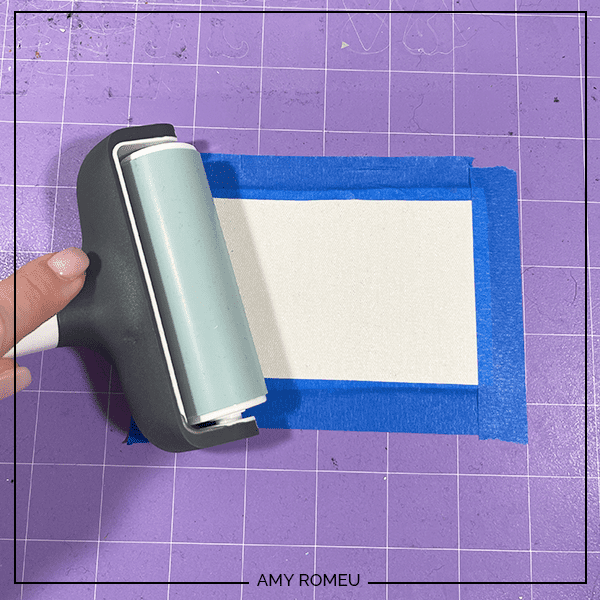 taped chunky glitter being rolled with a brayer on a purple Cricut cutting mat